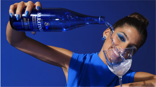 woman accessorized in saratoga cobalt blue pantone color pouring saratoga spring water
