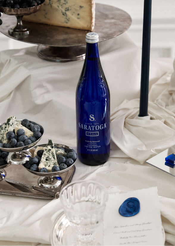 table set with blue cheeses blueberries and a bottle of saratoga spring water
