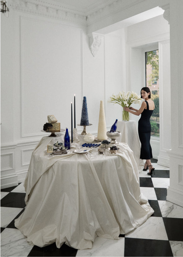 athena calderone arranging a vase of calla lilies in a stylish white dining room