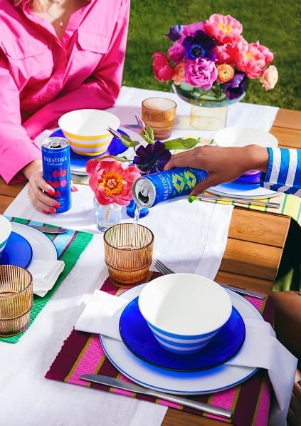 An outdoor picnic table where people are pouring Saratoga Collection® flavored sparkling water.